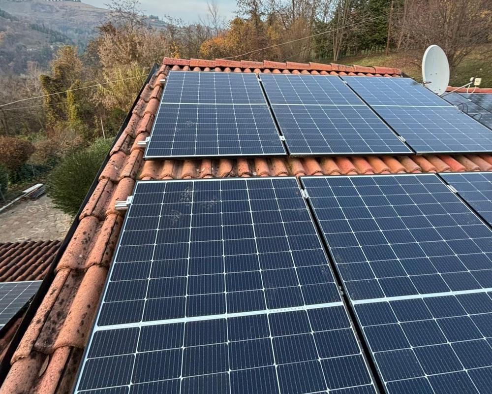Pannelli fotovoltaici installati da N&V sul tetto in coppi di un'abitazione, con vista sulle colline